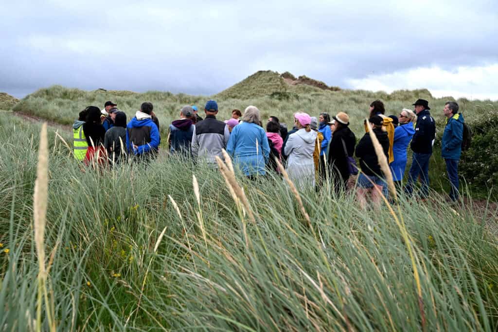Group of people walking in the sand dunes in the Maharees